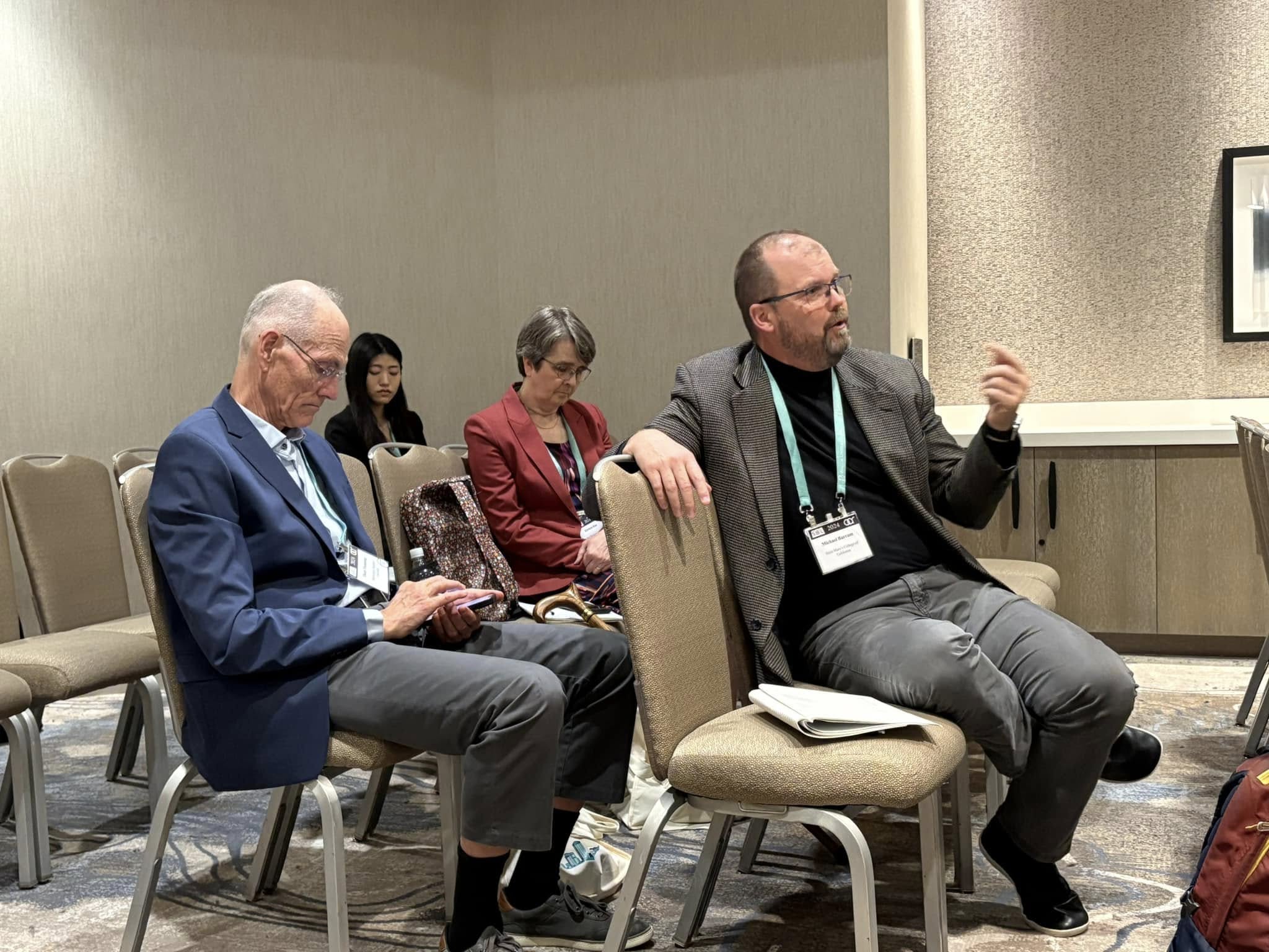 Seated participants in discussion, with one person gesturing as they speak.